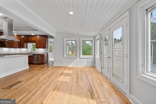 unfurnished living room featuring light wood-style floors, a wealth of natural light, visible vents, and vaulted ceiling