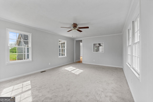 spare room featuring visible vents, ornamental molding, light carpet, ceiling fan, and baseboards