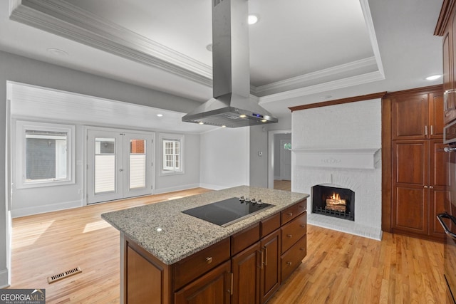 kitchen with open floor plan, visible vents, island exhaust hood, and black electric cooktop