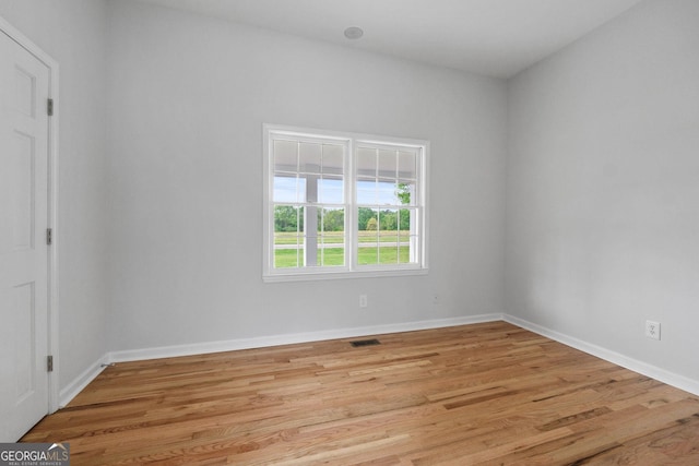 spare room with light wood-style flooring, visible vents, and baseboards