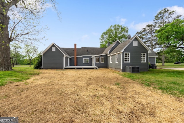 rear view of house with a lawn, a chimney, and cooling unit