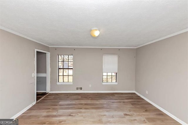 spare room featuring a textured ceiling, wood finished floors, a wealth of natural light, and baseboards