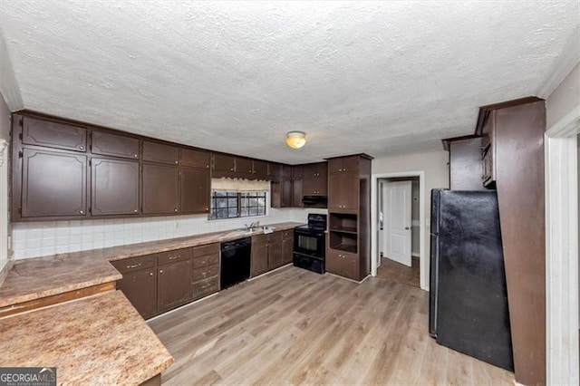 kitchen featuring light countertops, light wood-style flooring, dark brown cabinets, under cabinet range hood, and black appliances