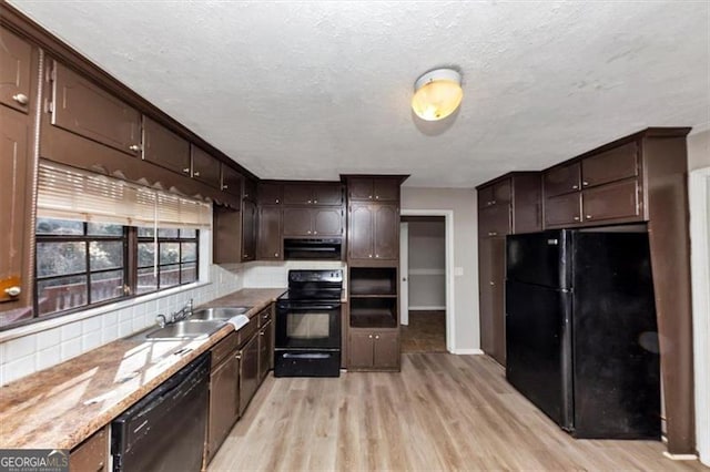 kitchen with dark brown cabinetry, a sink, light wood-style floors, ventilation hood, and black appliances