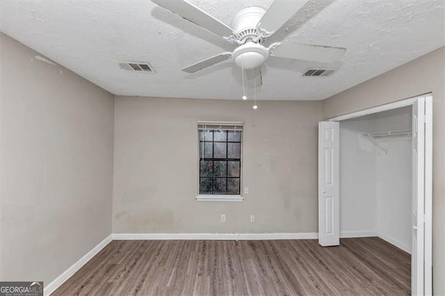 unfurnished bedroom featuring a textured ceiling, wood finished floors, visible vents, and baseboards