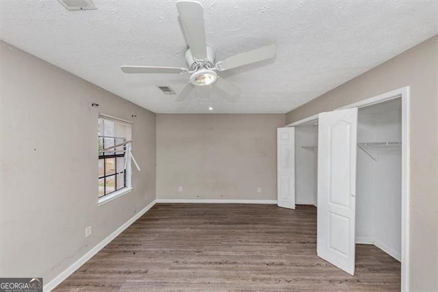 unfurnished bedroom with a textured ceiling, wood finished floors, visible vents, and baseboards