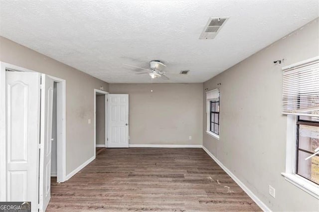 empty room with a textured ceiling, baseboards, visible vents, and light wood-style floors