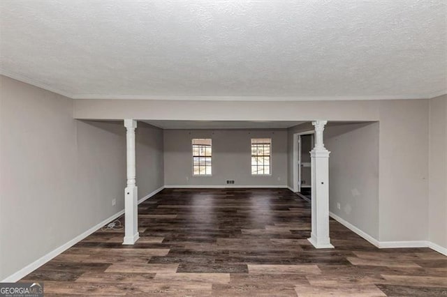 unfurnished living room with ornamental molding, a textured ceiling, baseboards, and wood finished floors