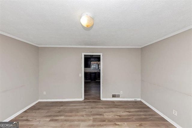 empty room featuring visible vents, a textured ceiling, baseboards, and wood finished floors