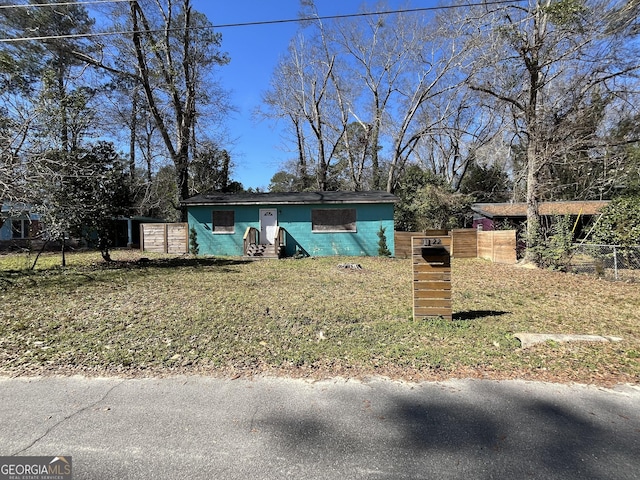 view of front facade with fence, concrete block siding, and a front yard