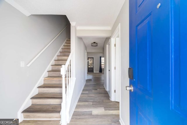 foyer with baseboards, stairway, light wood finished floors, and a textured ceiling