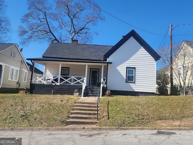 bungalow-style home featuring covered porch, a front lawn, roof with shingles, and a chimney