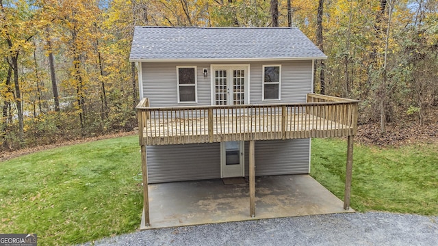 view of front facade featuring french doors, roof with shingles, a patio area, a front lawn, and a wooden deck