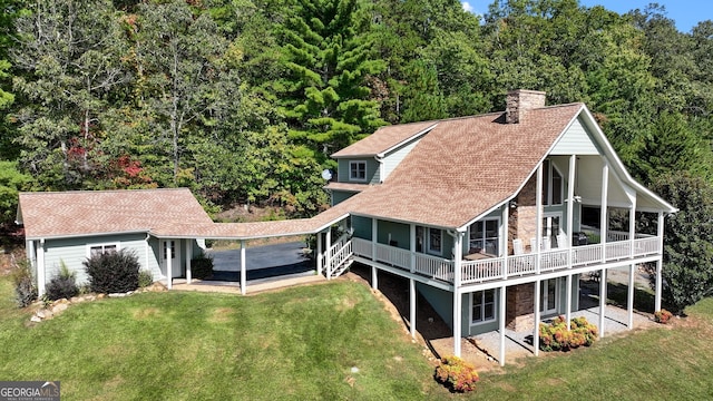 rear view of house featuring a chimney, a deck, a lawn, and roof with shingles