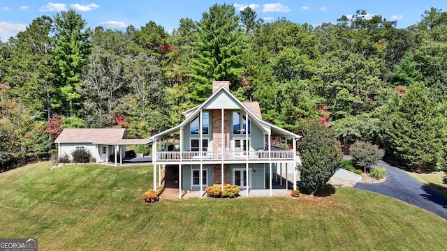 back of property with a lawn, a chimney, and a wooden deck