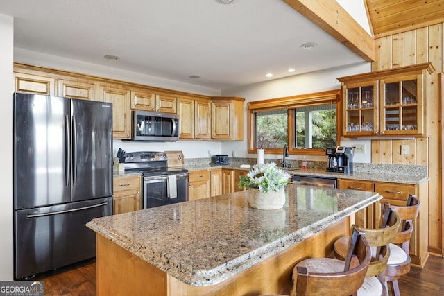 kitchen featuring light stone counters, dark wood-style floors, appliances with stainless steel finishes, glass insert cabinets, and a kitchen island