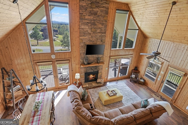 living area featuring high vaulted ceiling, wood walls, a fireplace, wood finished floors, and wood ceiling