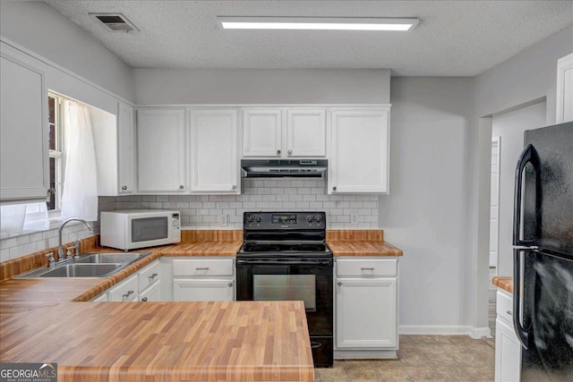 kitchen featuring under cabinet range hood, a sink, visible vents, wooden counters, and black appliances