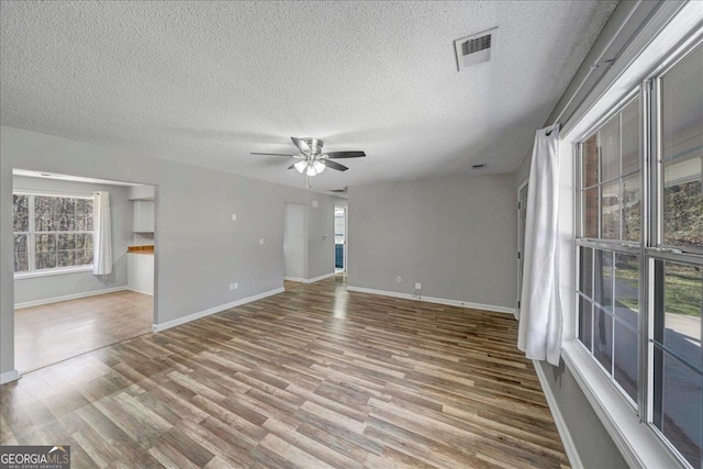 unfurnished room featuring baseboards, ceiling fan, visible vents, and wood finished floors