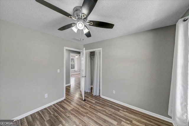 unfurnished bedroom with a textured ceiling, ceiling fan, wood finished floors, and baseboards