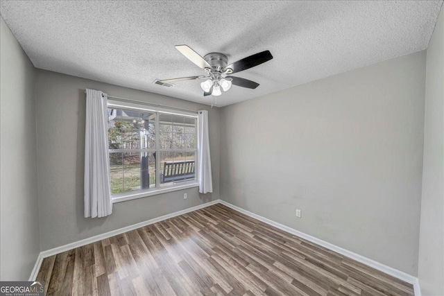 spare room featuring ceiling fan, a textured ceiling, baseboards, and wood finished floors