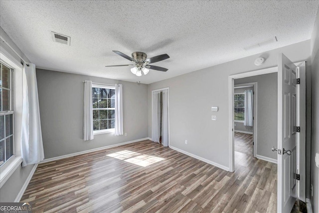 unfurnished bedroom with ceiling fan, wood finished floors, visible vents, and baseboards