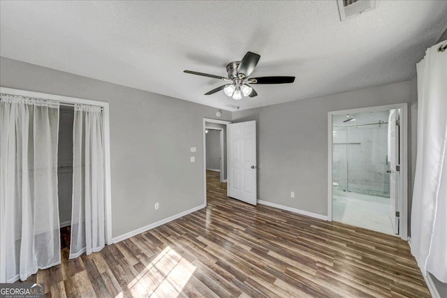 unfurnished bedroom with a textured ceiling, dark wood-type flooring, a ceiling fan, visible vents, and baseboards