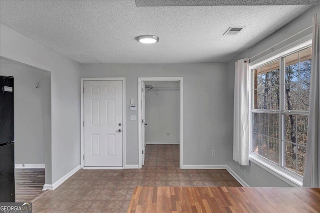 interior space with visible vents, a textured ceiling, and baseboards