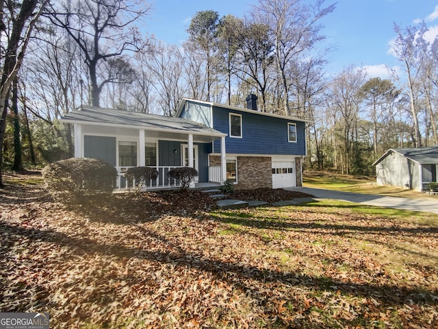 split level home with stone siding, covered porch, driveway, and a garage