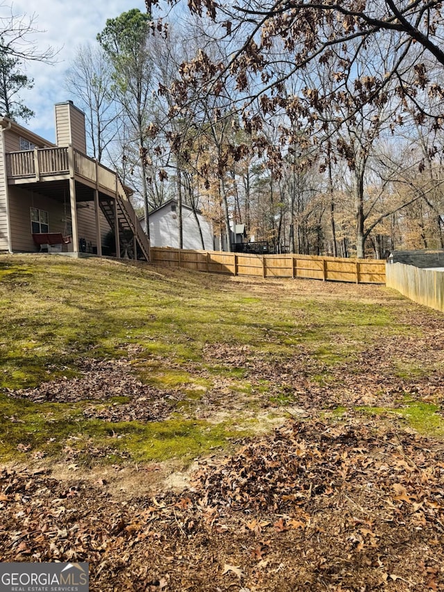 view of yard with fence, a deck, and stairs