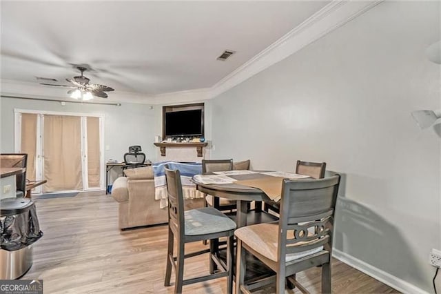 dining room with visible vents, ornamental molding, light wood-style floors, ceiling fan, and baseboards