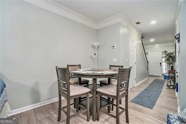 dining room featuring light wood-style floors, visible vents, baseboards, and ornamental molding