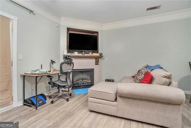 living area with ornamental molding, a fireplace, wood finished floors, and visible vents