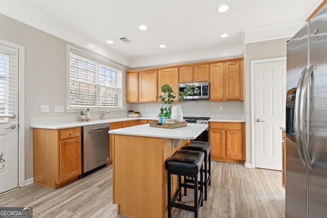 702 Berkeley Ter, Canton, GA 30115 - kitchen with appliances with stainless steel finishes, light wood-style floors, light countertops, a breakfast bar, and ornamental molding