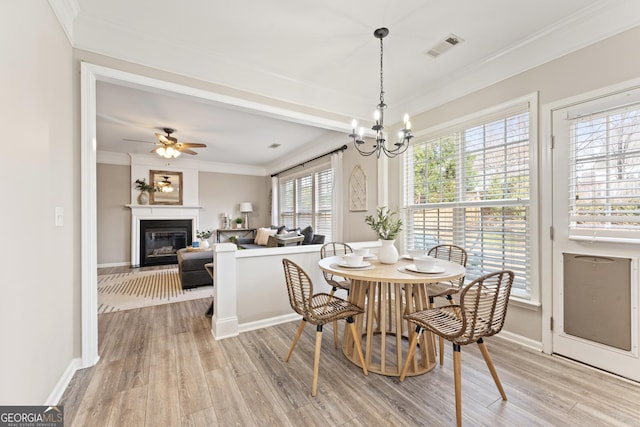 702 Berkeley Ter, Canton, GA 30115 - dining space featuring ornamental molding, light wood-style flooring, a glass covered fireplace, a chandelier, and ceiling fan