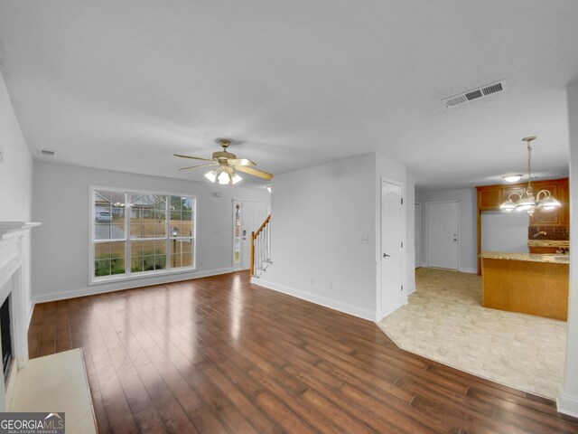 641 Morningside Dr, Stockbridge, GA 30281 - unfurnished living room featuring a fireplace with flush hearth, stairs, visible vents, and dark wood finished floors