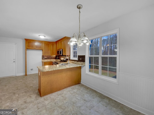 641 Morningside Dr, Stockbridge, GA 30281 - kitchen with light stone counters, brown cabinets, decorative light fixtures, stainless steel microwave, and a peninsula