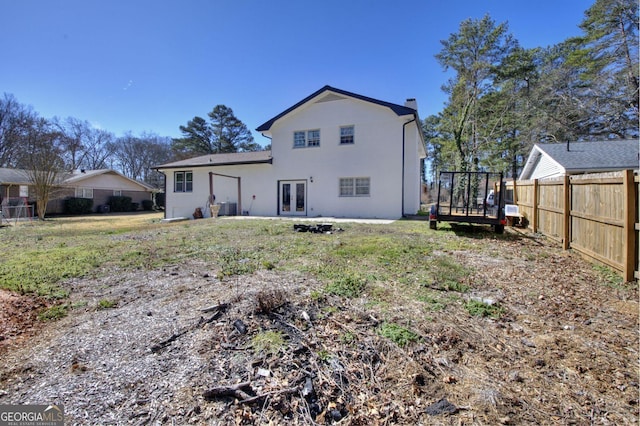 back of house featuring french doors, a fenced backyard, a chimney, and stucco siding