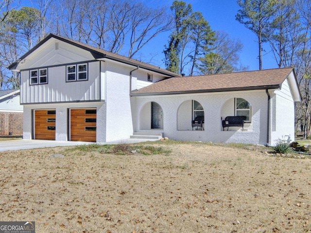 view of front facade featuring covered porch, brick siding, a front lawn, and concrete driveway