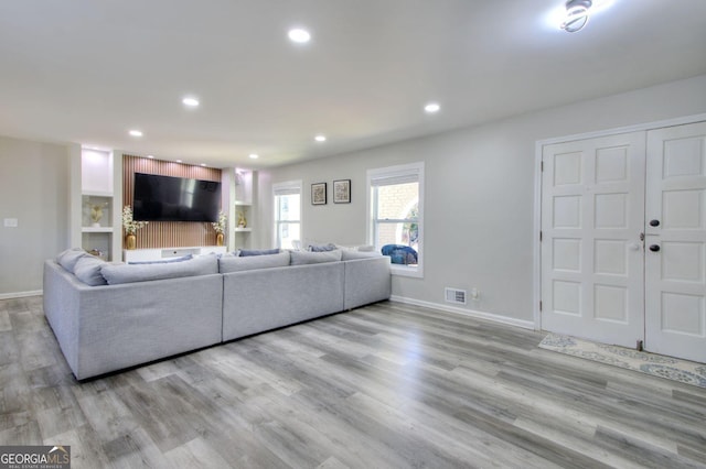 living area featuring baseboards, light wood-type flooring, visible vents, and recessed lighting