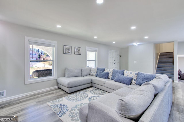 living room featuring light wood-style flooring, recessed lighting, visible vents, baseboards, and stairs