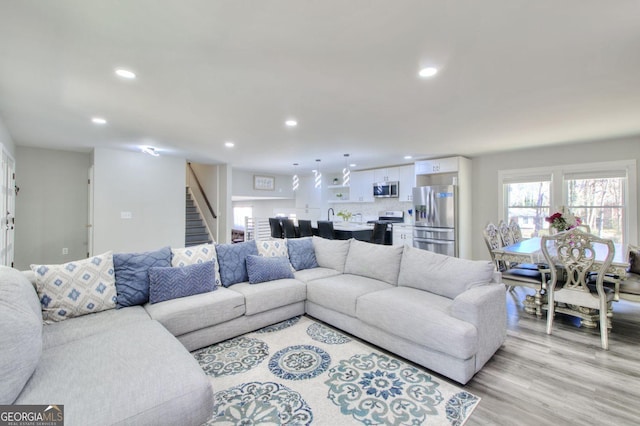 living area featuring light wood-style floors, recessed lighting, and stairs