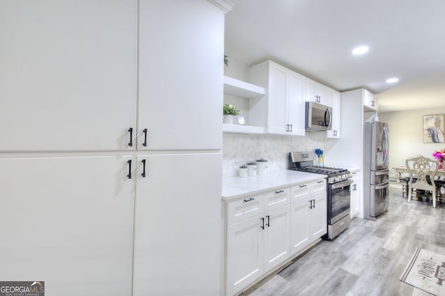 kitchen with open shelves, stainless steel appliances, tasteful backsplash, light wood-style flooring, and white cabinetry