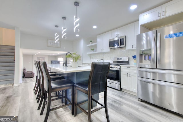 kitchen with stainless steel appliances, light countertops, white cabinetry, and open shelves