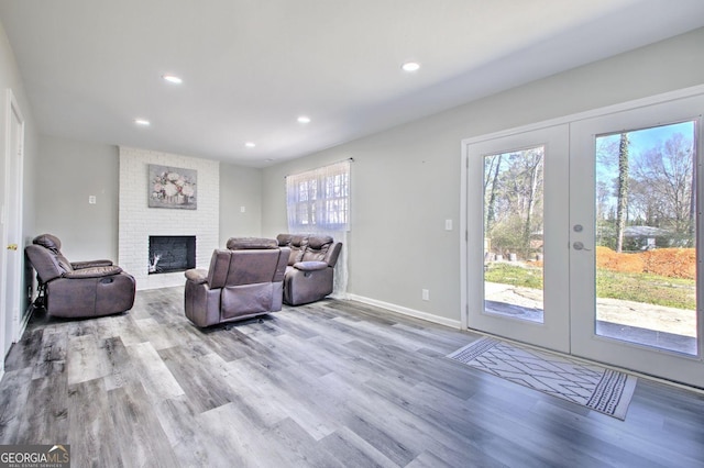 living area with light wood finished floors, baseboards, french doors, a fireplace, and recessed lighting