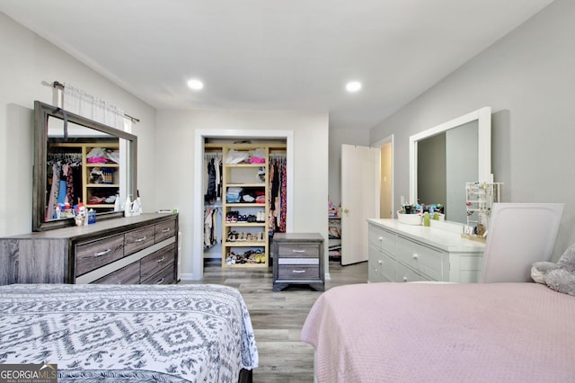 bedroom with recessed lighting, a closet, light wood-style flooring, and a spacious closet