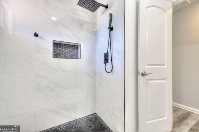 full bath with baseboards, a tile shower, and wood finished floors