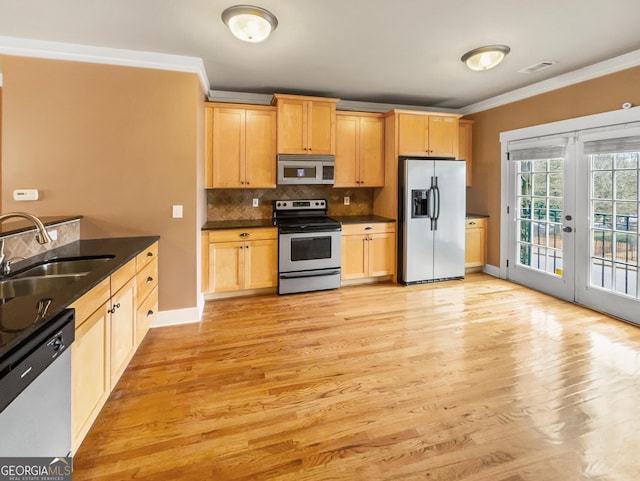 kitchen with stainless steel appliances, a sink, ornamental molding, french doors, and backsplash