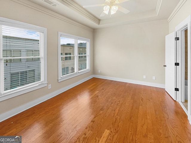 unfurnished room featuring a raised ceiling, visible vents, crown molding, and wood finished floors