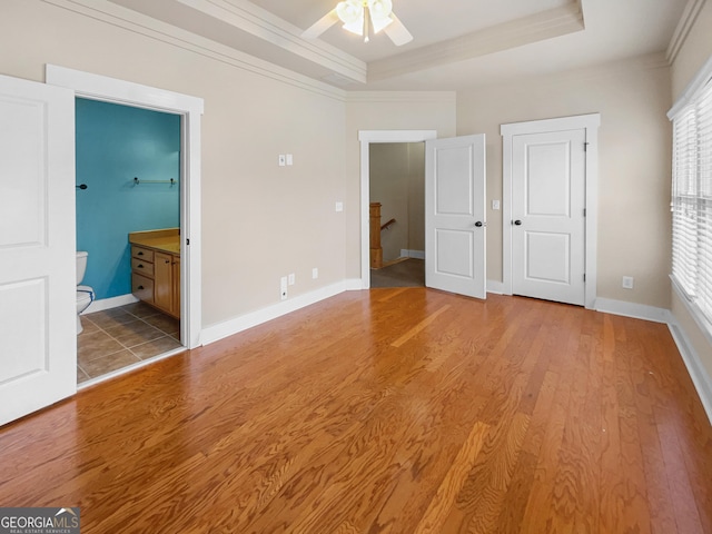 unfurnished bedroom with light wood finished floors, baseboards, a tray ceiling, and ornamental molding